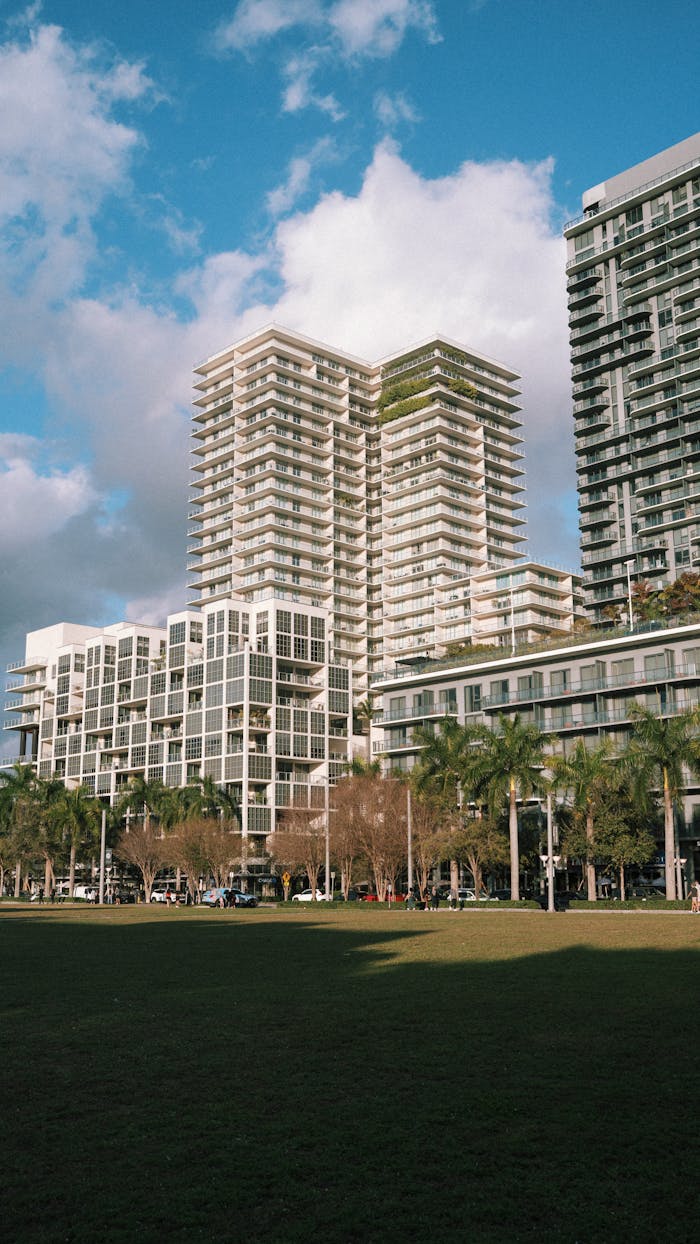 Tall modern skyscrapers against blue sky with park area in urban setting.