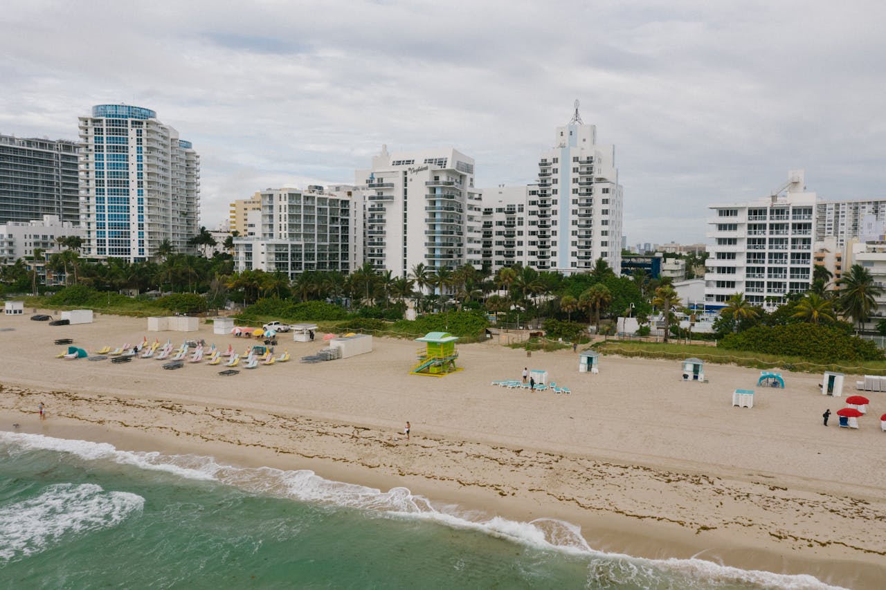 Aerial view of beachfront cityscape with tall buildings and sandy shore.